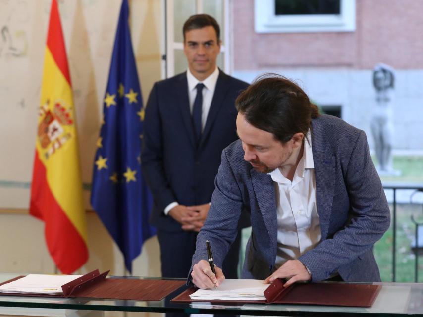Iglesias firma el acuerdo con Sanchez en la Moncloa.