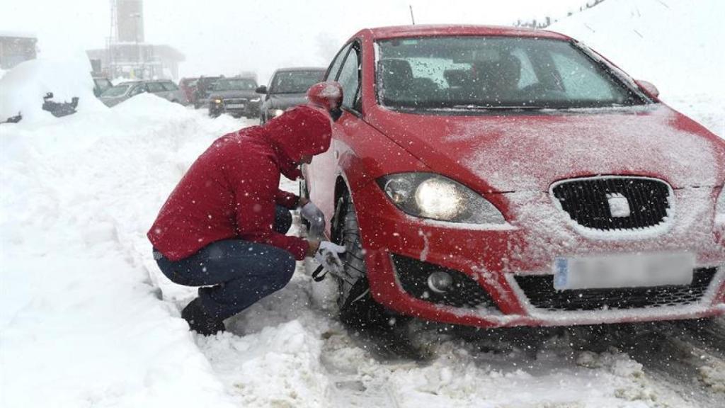 Un hombre pone las cadenas a su coche en el Puerto de Pajares (León).