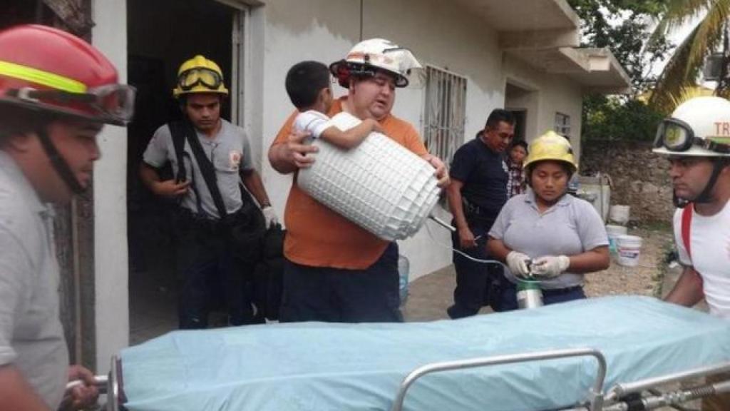 Los bomberos trasladando al niño para poder sacarlo del bombo