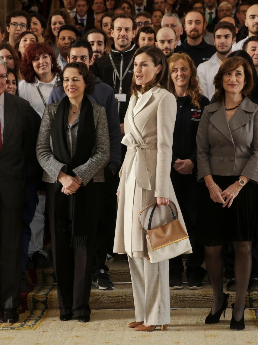 La reina ha completado su 'outfit' con un bolso camel y blanco roto de Carolina Herrera.