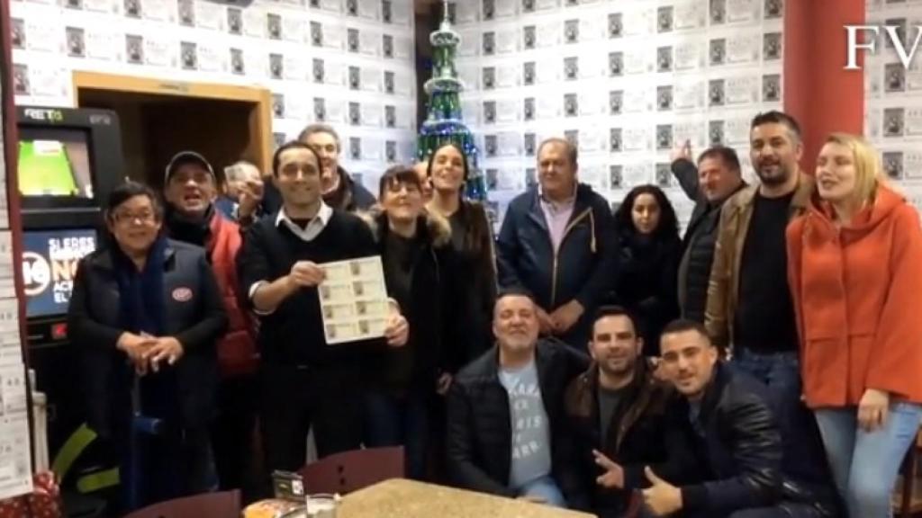 José Ramón, sujetando los décimos, junto a los clientes en el bar Varillas.