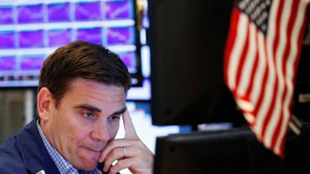 Un gestor mira una pantalla de cotización con gesto preocupado.