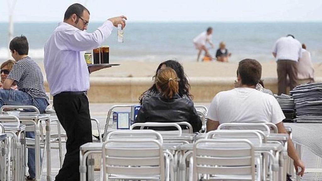 Un camarero sirviendo a unos clientes en una playa.