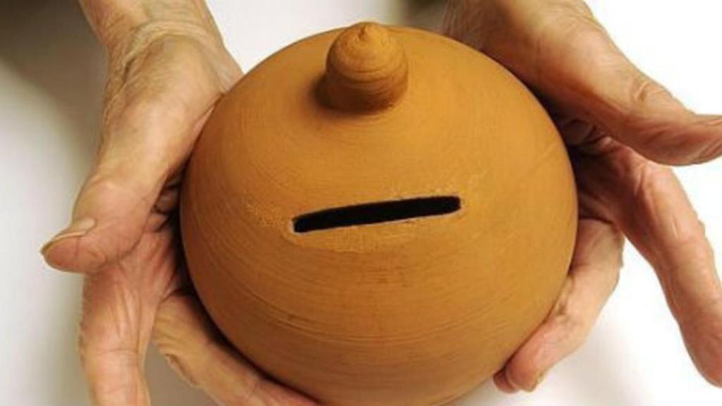 Una anciana sostiene una hucha de barro.