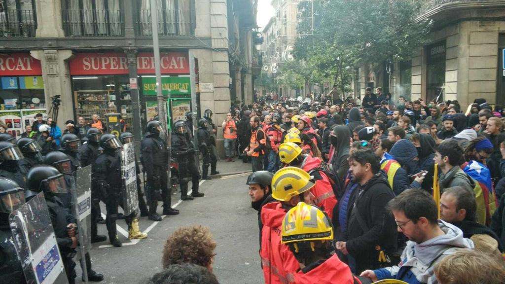 Agentes de la Brimo frente a un cordón de bomberos en la calle Fusteria.