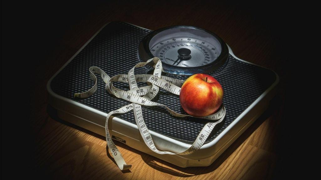 Una manzana y una cinta métrica encima de una báscula.