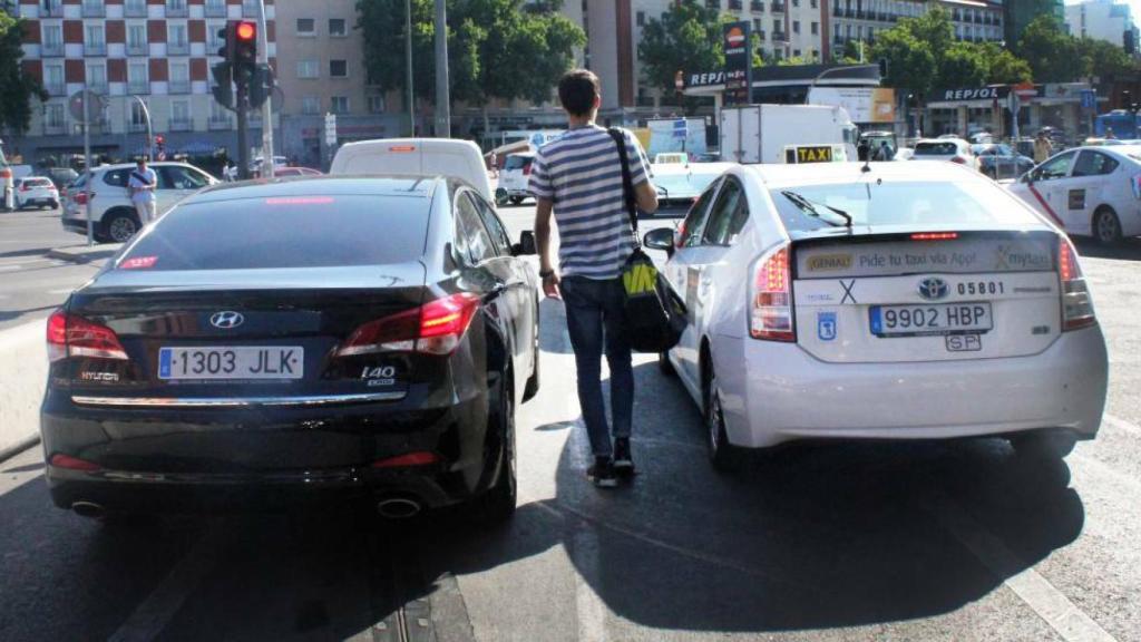 Un ciudadano entre una VTC y un Taxi en Madrid.