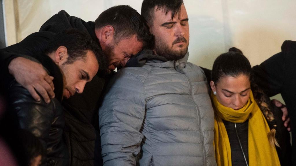 David, el dueño de la finca, apoya su cabeza sobre el hombro del padre de Julen, que viste un abrigo gris