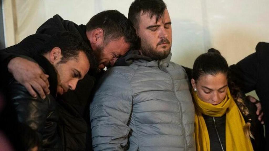 David Serrano (segundo por la izquierda) apoya su rostro mientras llora en el hombro de José Roselló, padre de Julen, que abraza a Victoria, la mamá del niño.