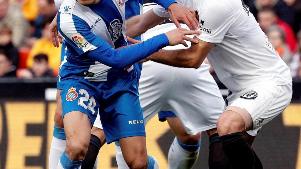 Wu Lei pugna con un jugador del Valencia en el partido de Liga entre ambos