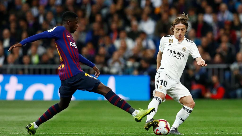 Modric intenta evitar la entrada de Dembelé