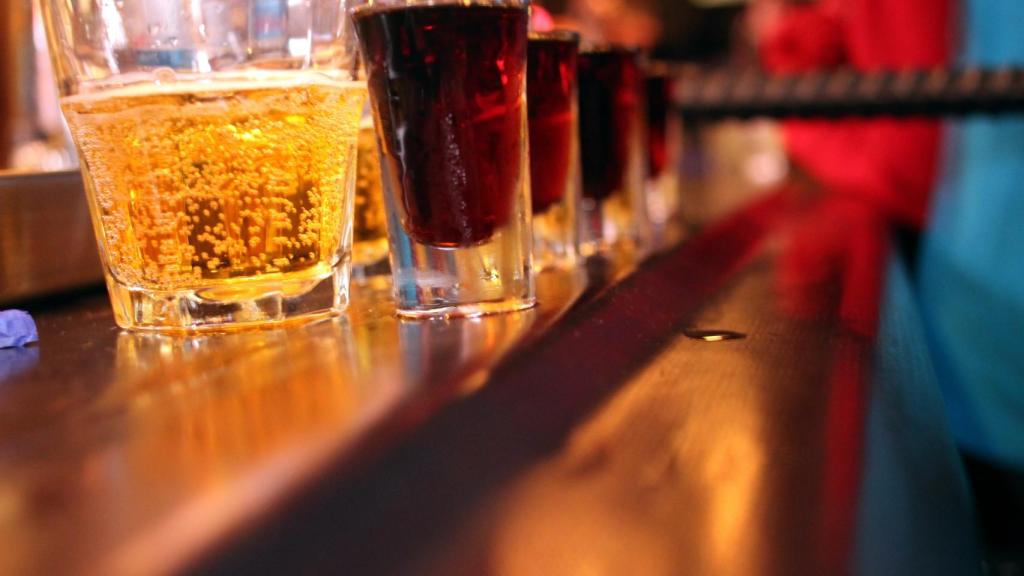 Chupitos con alcohol apunto de ser introducidos en un vaso con bebida energética