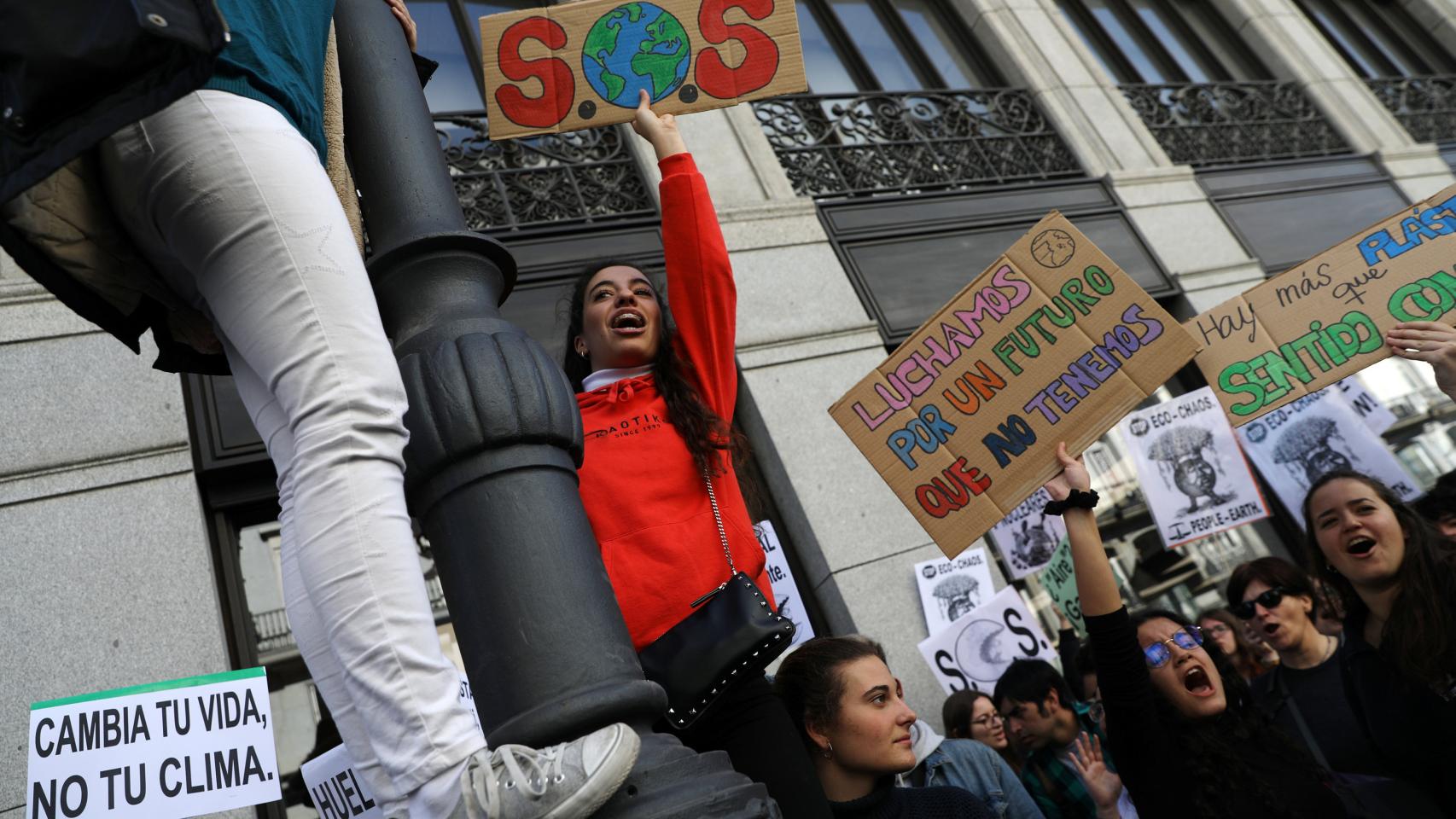 Una joven se sube a una farola durante la manifestación en Madrid.