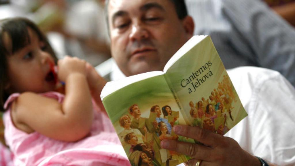 Un testigo de Jehová con una niña en brazos durante una celebración.