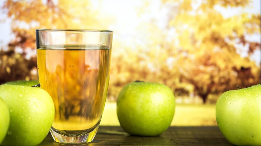 Un vaso de sidra junto a unas cuantas manzanas