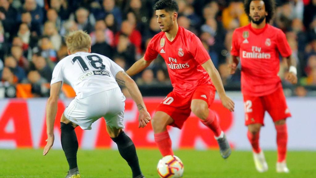 Marco Asensio controla el balón ante un jugador del Valencia
