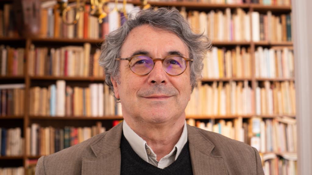 Andrés Trapiello en su casa, con su librería al fondo.