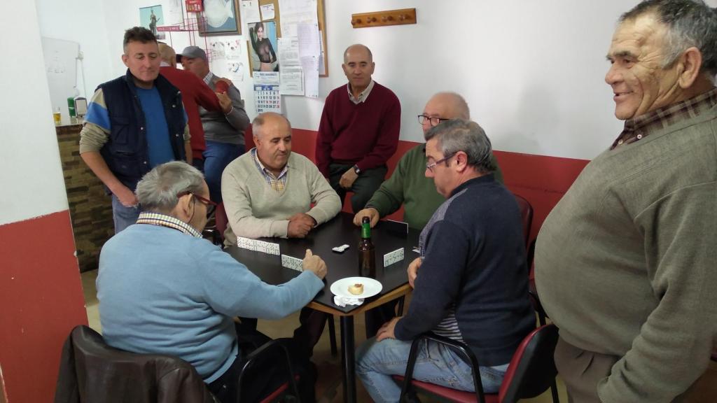 Vecinos de Benizar jugando una partida de dominó en la cantina del Centro Social y Cultural situado frente a la plaza Juan Domingo.
