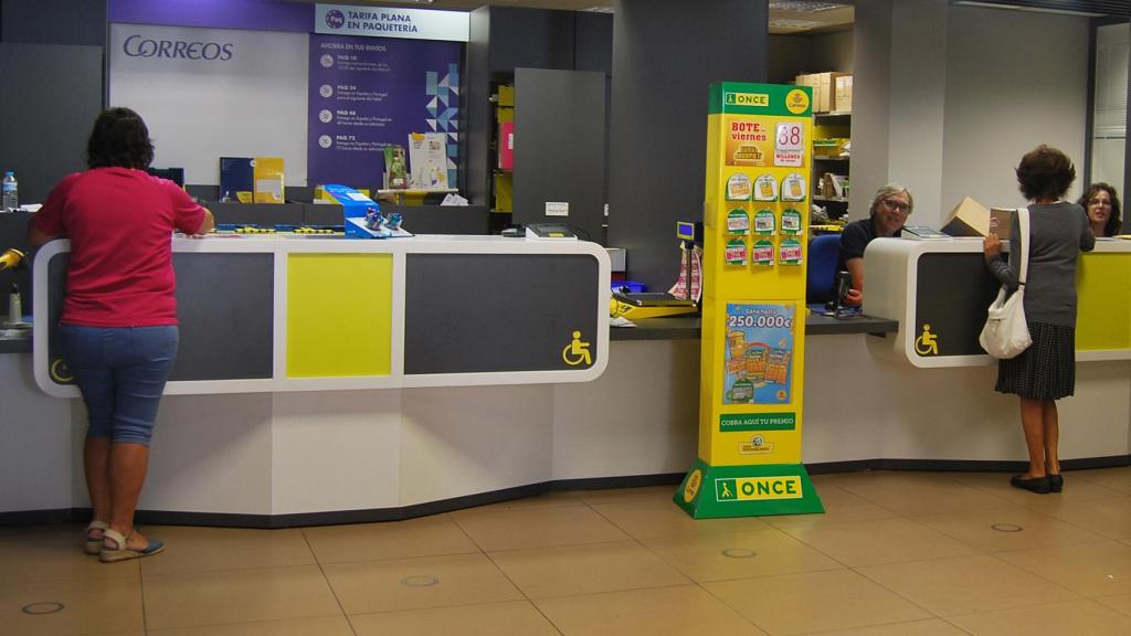 Una oficina de Correos con la publicidad de los productos de la ONCE.