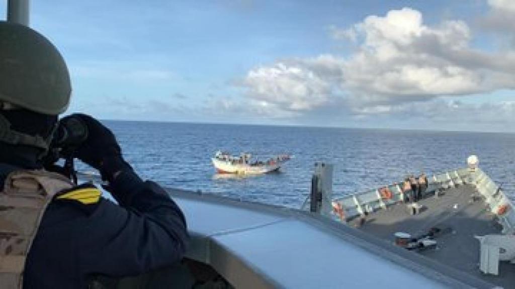 Un miembro de la dotación de la Navarra estudia los movimientos del barco tomado por los piratas.