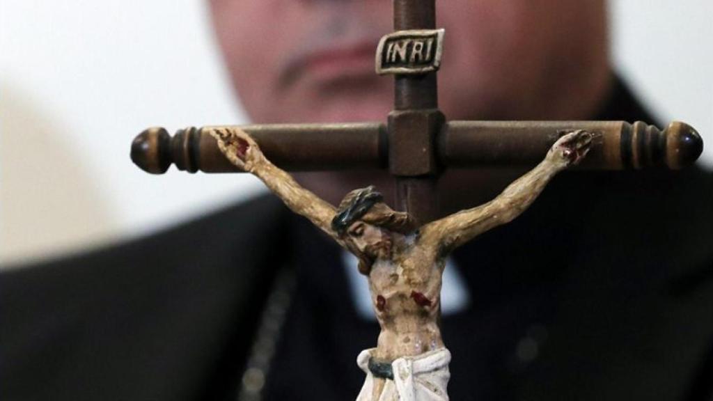 Imagen de archivo de una cruz frente a un sacerdote.