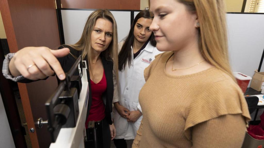 La prof. Cooper junto a una alumna de doctorando pesando a una de las participantes en el estudio.