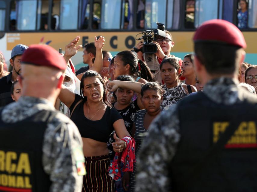 Los familiares de los presos protestan ante la mirada de la policía.