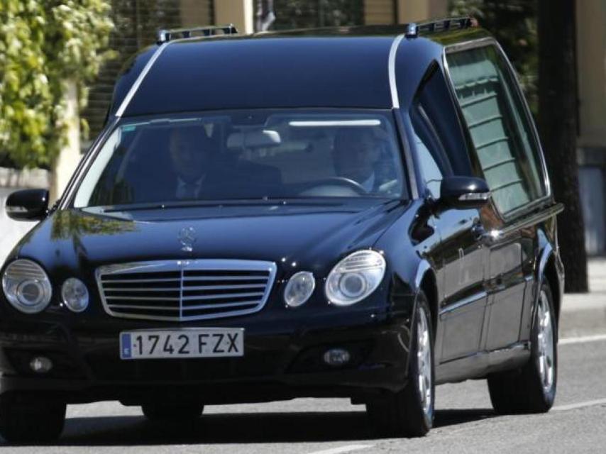 Dos empleados de una funeraria en un coche que traslada el féretro de un difunto.