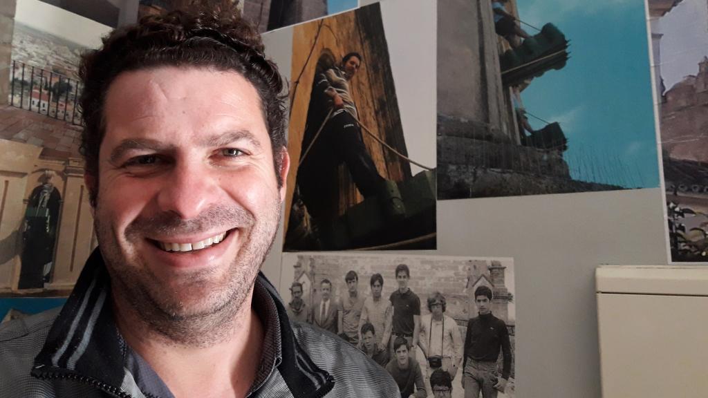 Carlos Palacios, junto a una foto en la que aparece subido a una campana en Utrera.