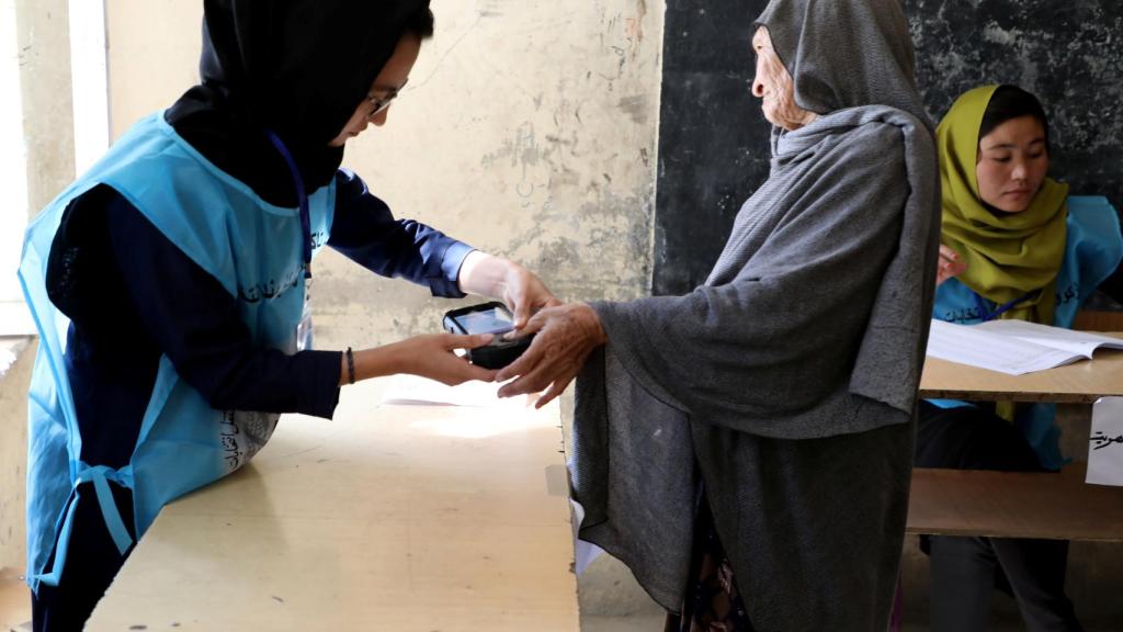 Los trabajadores de la comisión electoral comprueban las huellas de los votantes.