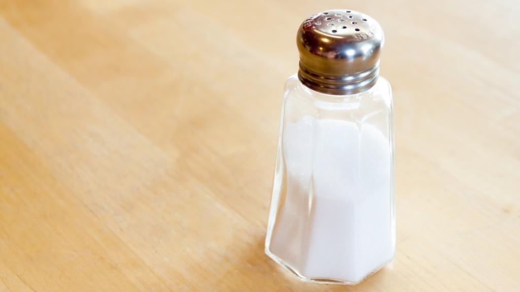 El típico salero de cristal colocado sobre una mesa de madera.