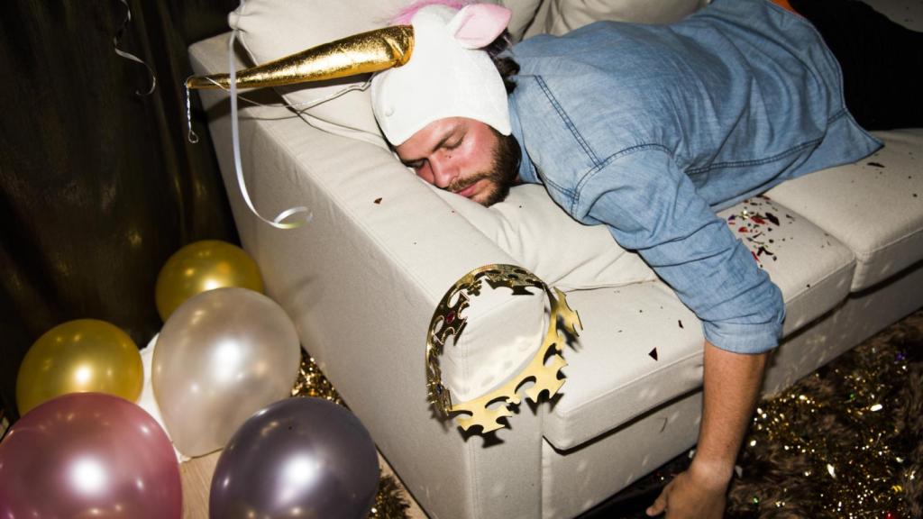 Un hombre descansa en un sofá tras una noche de consumo de alcohol.