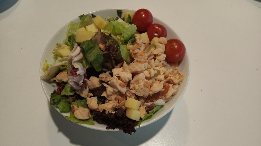 Ensalada de tres euros con lechuga, tomates cherrys, queso y pollo.