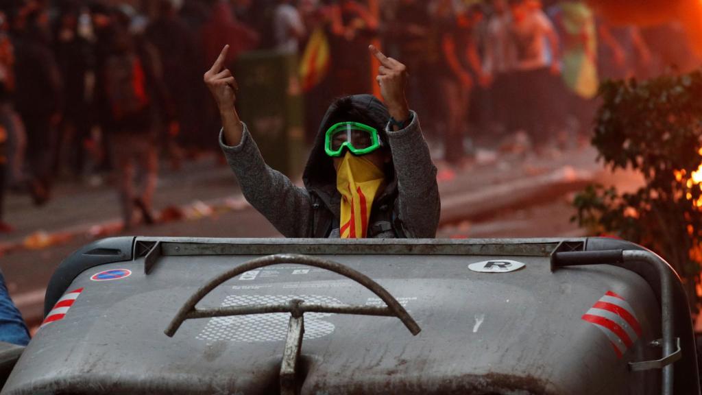 Uno de los radicales separatistas se enfrenta gestualmente a la Policía detrás de unos contenedores