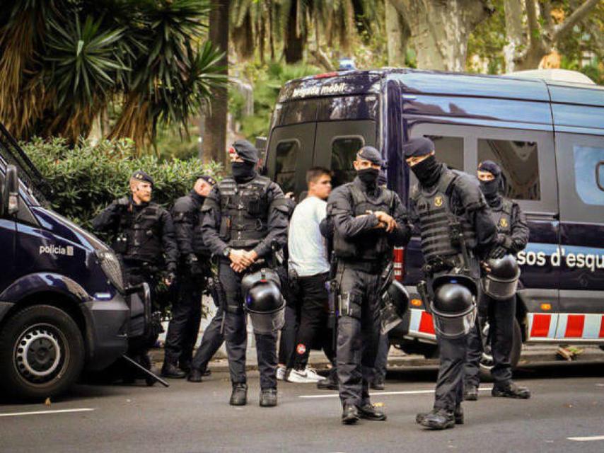Agentes de los Mossos d'Esquadra registran a un joven detenido, este pasado viernes.