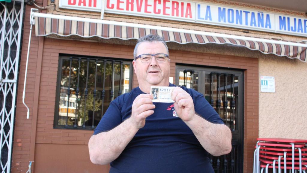 Daniel muestra su décimo de Lotería a las puertas de su bar.