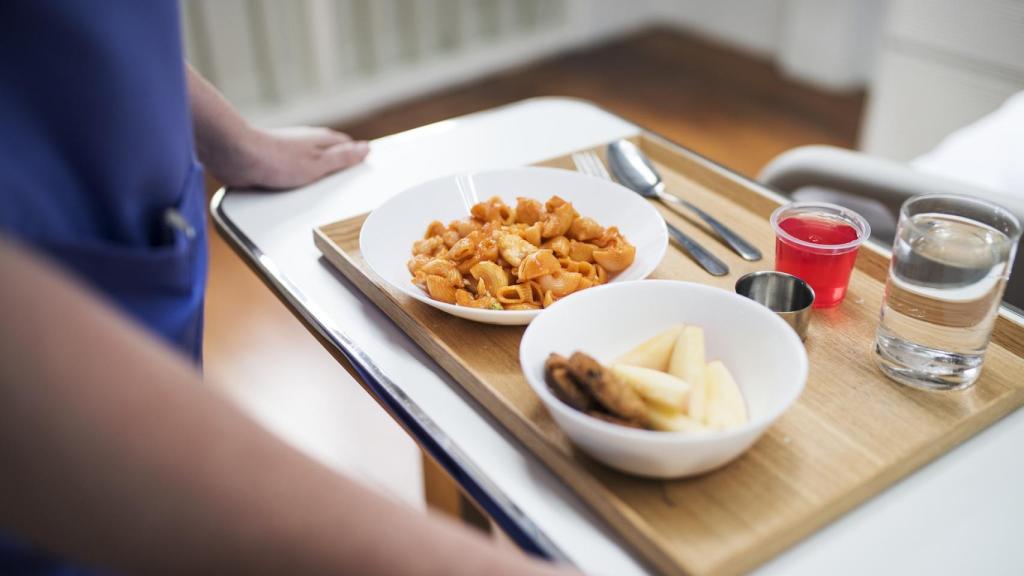 Un trabajador de un hospital lleva una bandeja con la comida de un paciente.
