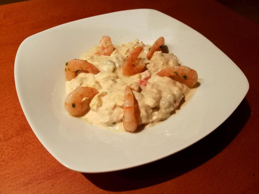Plato de ensaladilla rusa con gambas frescas y mayonesa.
