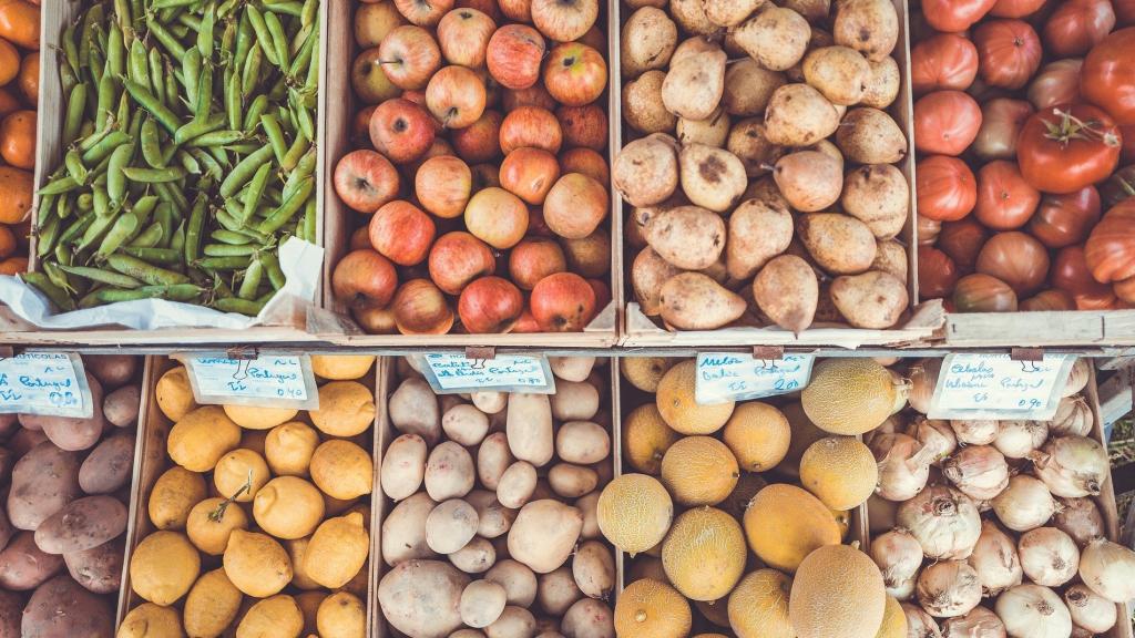 Distintas cajas con verduras y frutas de distinto tipo.