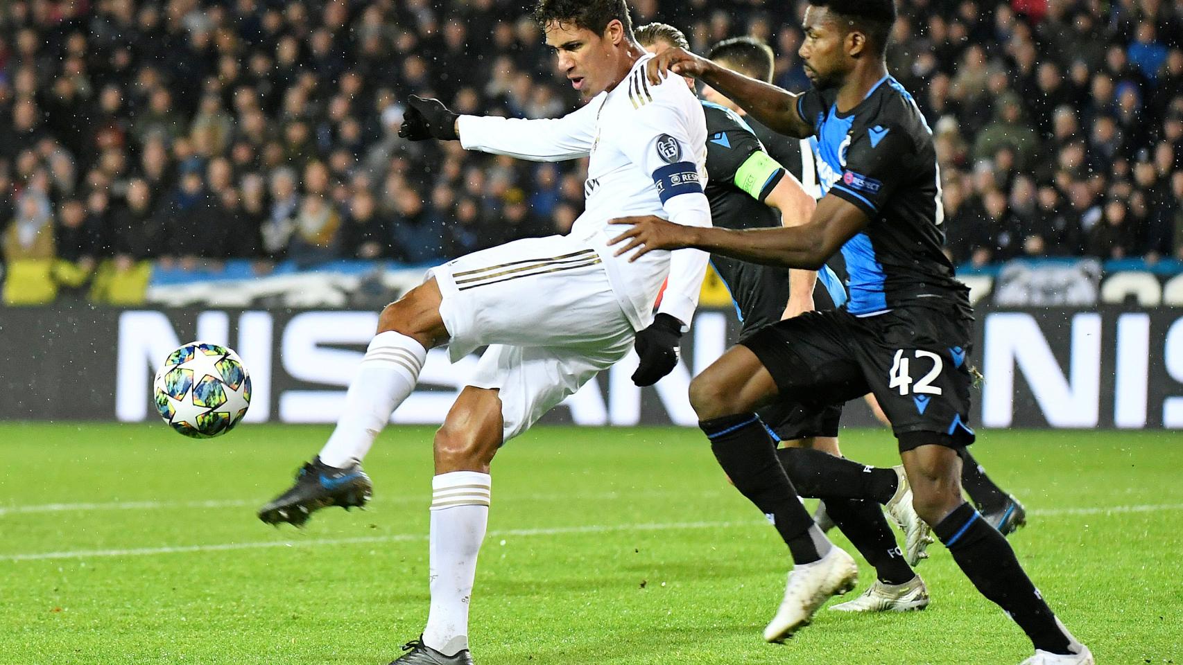 Emmanuel Dennis empuja a Raphael Varane