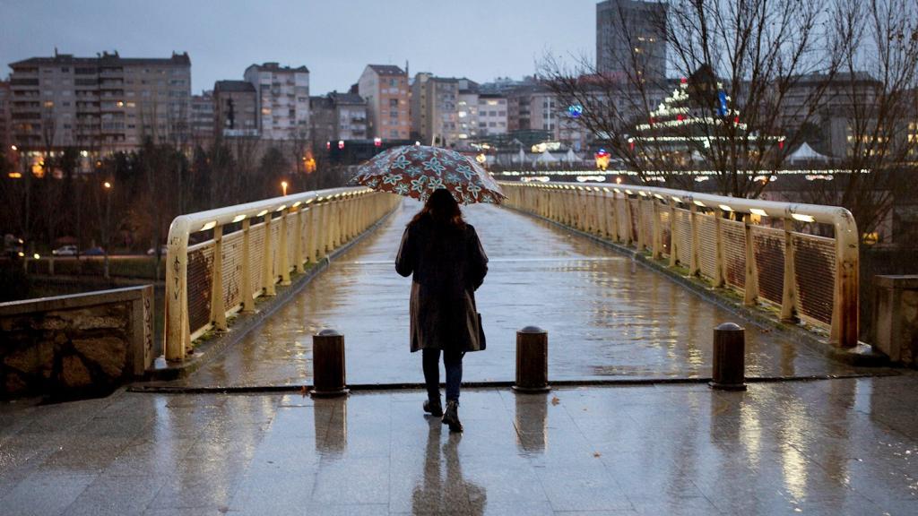 Una mujer se protege de la lluvia con un paraguas mientras pasea por las calles de EFE/ Brais Lorenzo. Orense.