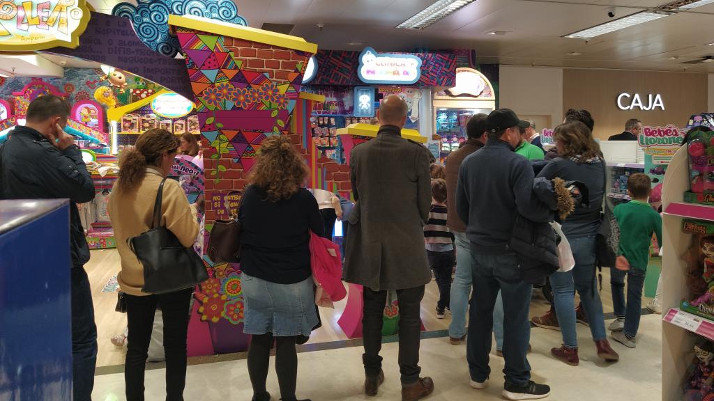 Padres y Madres esperan la cola de la 'Clínica Neonatal' para que 'Tania' atienda al muñeco de sus hijos.