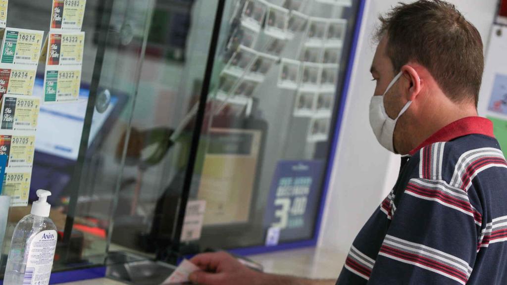 Un hombre comprando en una administración de Loterías y Apuestas del Estado en Valencia.