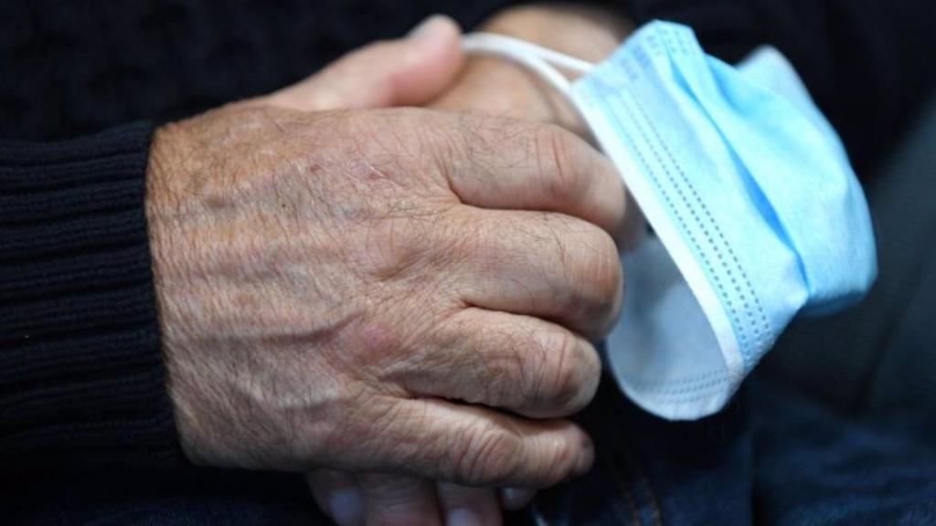 Una persona mayor toma una mascarilla entre sus manos