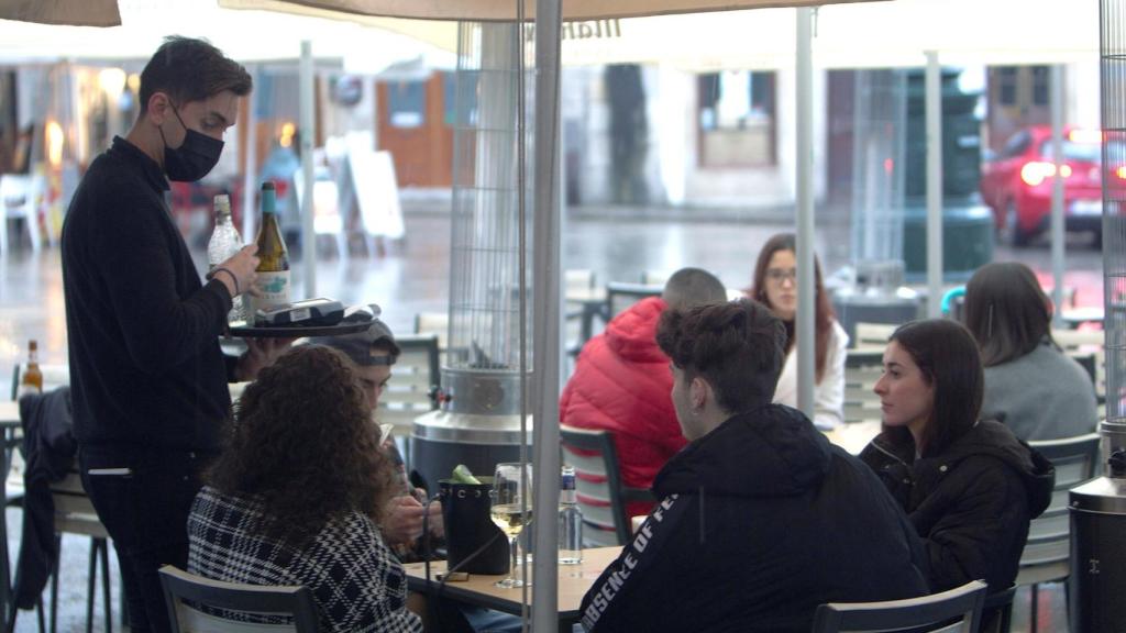 Un camarero atiende a unos clientes en una terraza en Vigo.