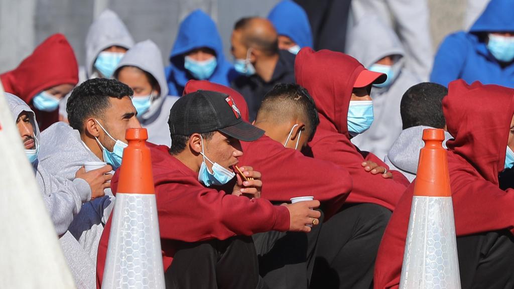 Varios inmigrantes rescatados al sur de Gran Canaria esperan a ser trasladados a Barranco Seco en el muelle de Arguineguín.