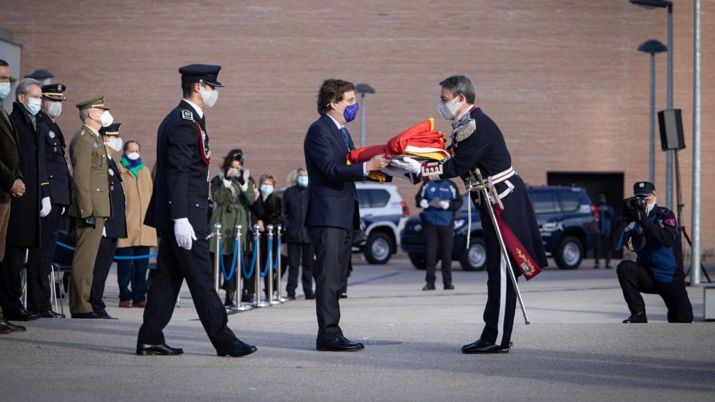 Almeida entrega la bandera nacional para su izado, en el cuartel de la Policía Municipal de Casa de Campo.