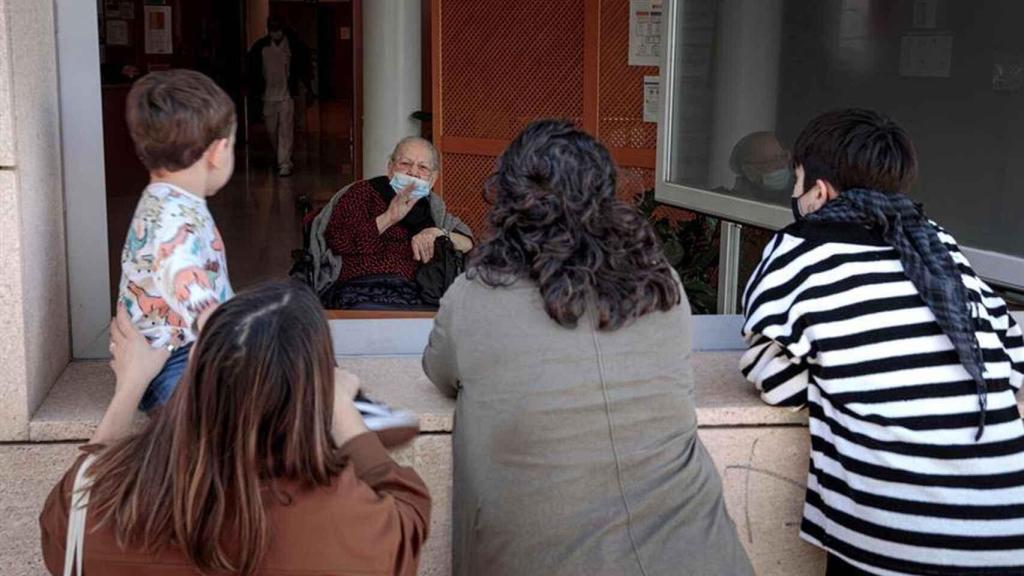 Un anciano saluda a su familia en su residencia.