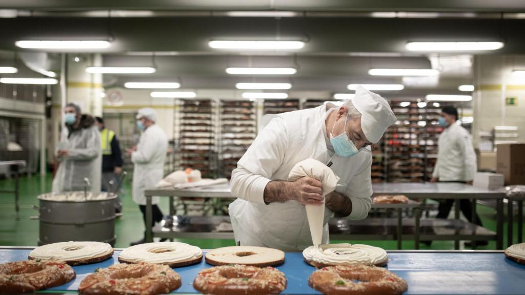 Un pastelero agrega nata a un roscón relleno.