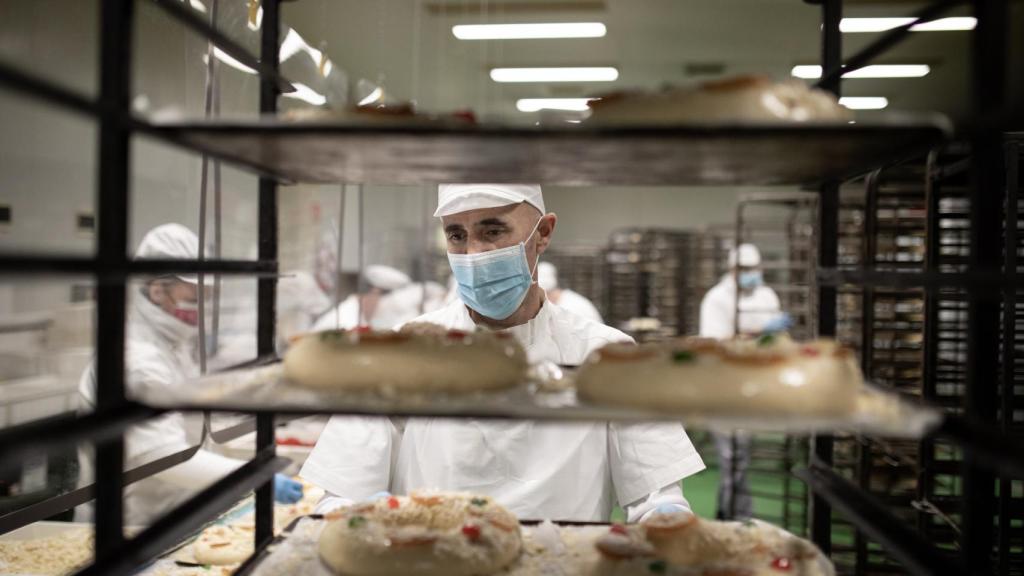 Un pastelero comprueba un carro de roscones antes de meterlos en el horno.